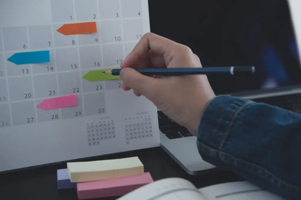 Mão segurando um lápis e riscando um calendário