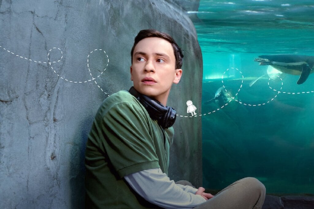Protagonista da série "Atypical" em frente a um aquário e olhando para o lado 