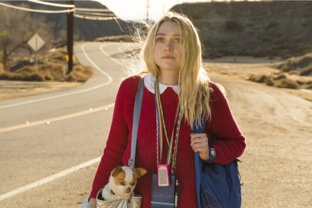 Atriz Dakota Fanning andando em uma estrada e segurando bolsas no filme "Tudo Que Quero"
