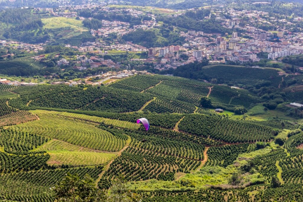 Vista do alto da Serra Negra com as montanhas e uma pessoa voando de parapente