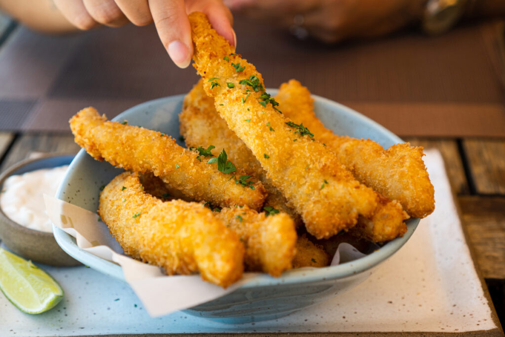 Iscas de peixe fritas em recipiente azul claro