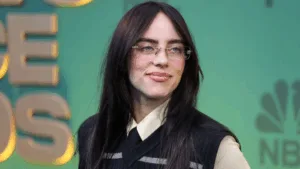 Billie Eilish com o cabelo preto e usando óculos de grau