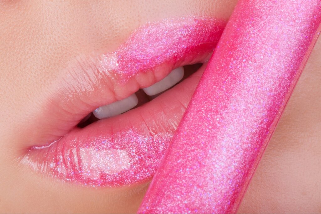 Glose em uma boca com lip gloss rosa brilhante 