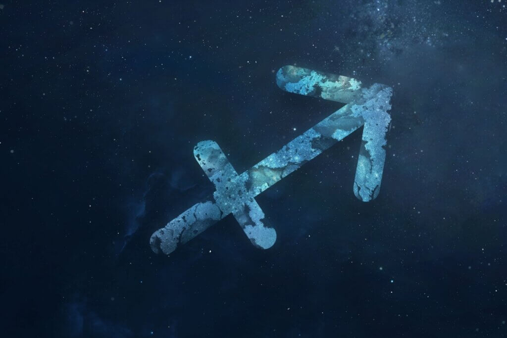 símbolo do signo de sagitário em um fundo azul marmorizado sobre fundo azul-escuro estrelado