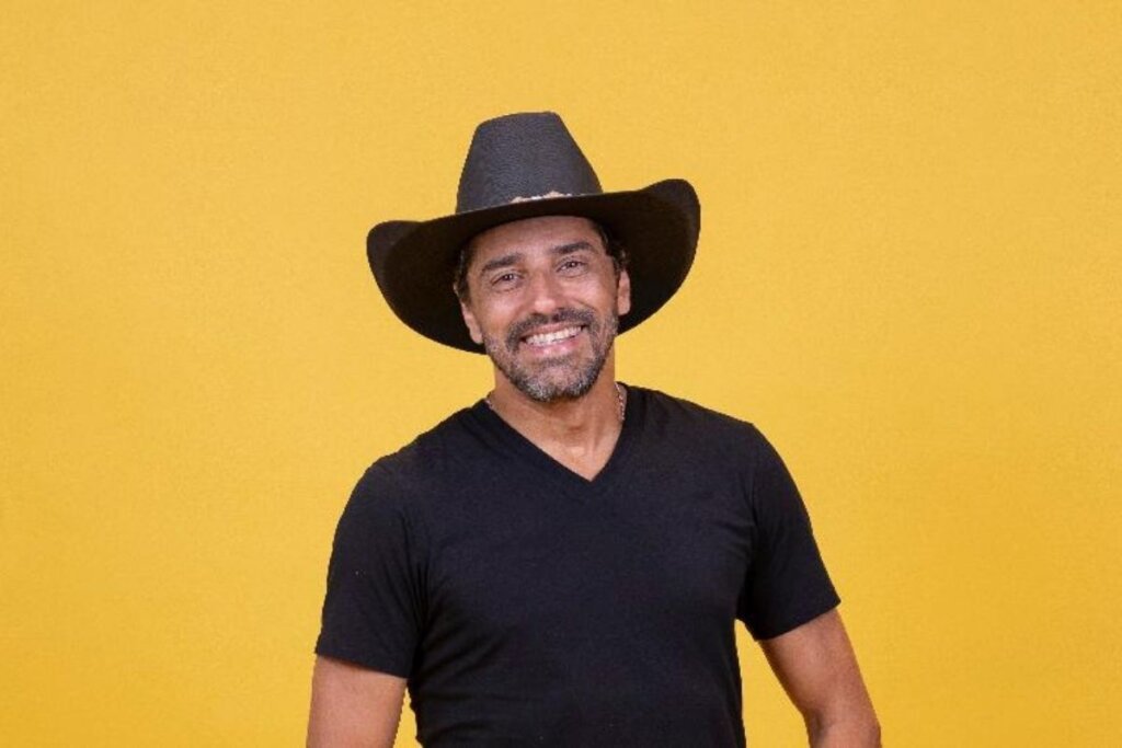 Alberto Cowboy posando para foto em um fundo amarelo 