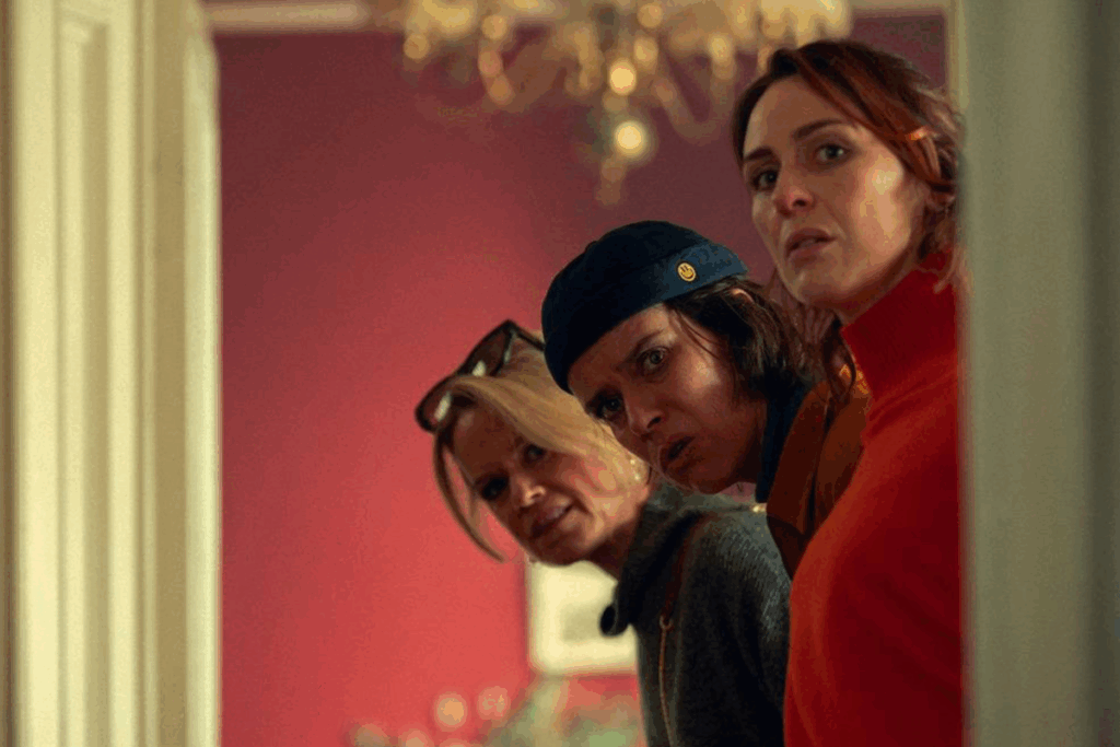 Três mulheres observando algo fora de cena em um ambiente interno