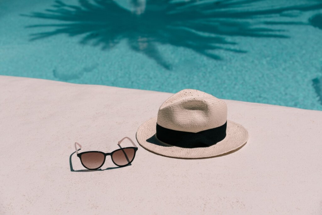 Óculos de sol e chapéu de palha na beira de uma piscina 